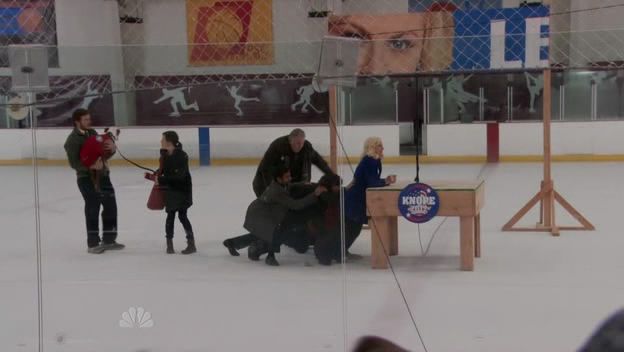 image of Leslie Knope and her gang sliding all over the ice at an ice rink while she tries to make it to a stage for a campaign speech