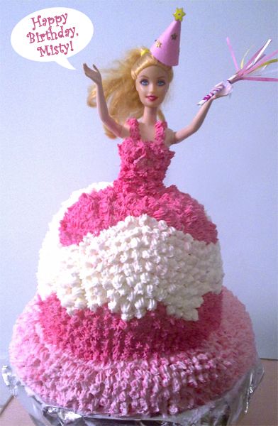 a Barbie cake in which the Barbie is wearing a pink gown and holding her hands in the air, with a paper party favor in one hand, to which I've added a dialogue bubble reading 'Happy Birthday, Misty!'