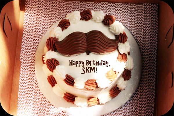 image of a birthday cake with a giant mustache on it, reading 'Happy Birthday, SKM!'