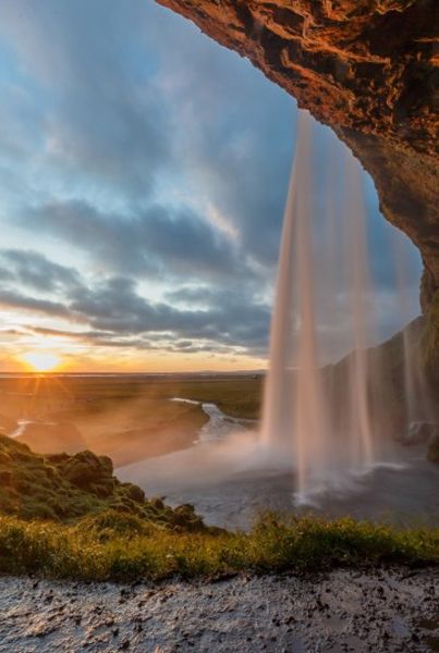 image of a waterfall falling over a cliffside at sunset