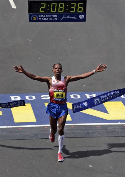 image of Meb Keflezighi, a think black man, crossing the finish line with his arms spread wide