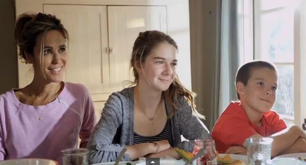 image of a woman, a teenage girl, and a tween boy, all white, sitting at a table smiling