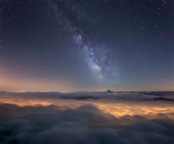 image of the Milky Way's galactic center visible above the clouds at night