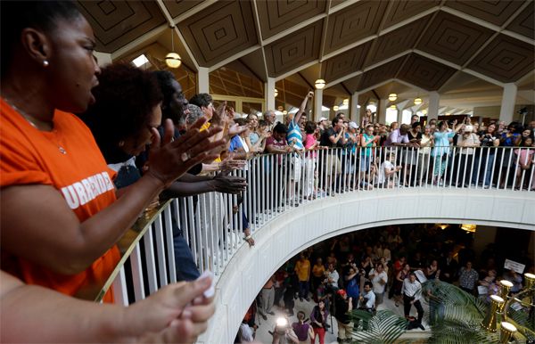 a mixed-race group of people protest at the North Carolina General Assembly building as part of a Moral Mondays demonstration