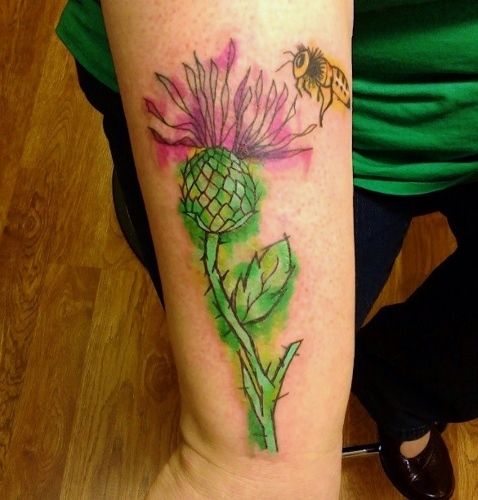 image of my right forearm featuring a tattoo of a thistle and a bee