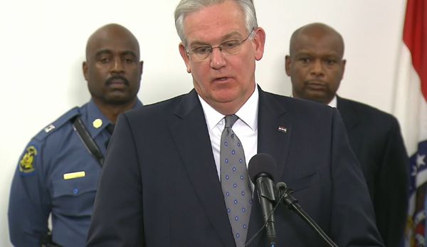 image of Governor Nixon, a middle-aged white man, flanked by two black officers, standing just behind him