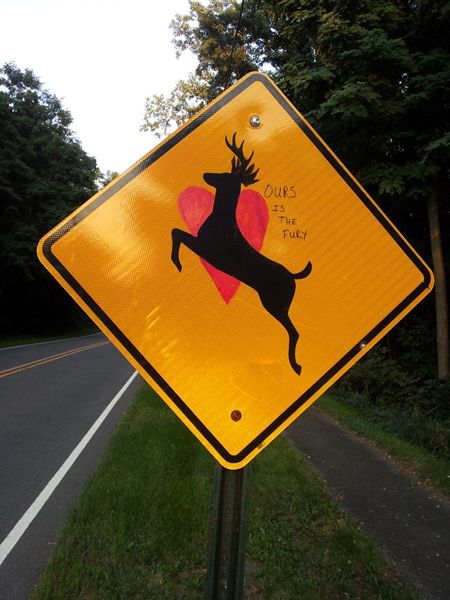 image of a deer crossing sign with a red heart and the words 'Ours is the fury' added to it
