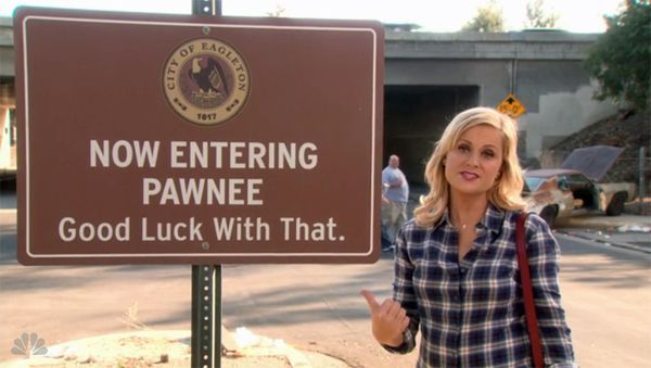 image of Leslie Knope standing next to a sign reading 'Now Entering Pawnee: Good Luck With That.'