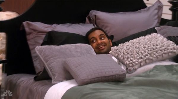 image of Tom Haverford (Aziz Ansari) lying in a heavily pillowed bed with only his wee head sticking out