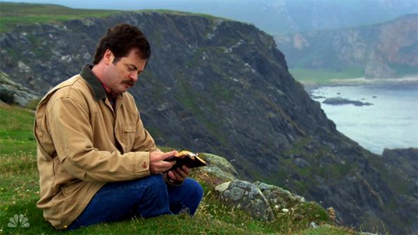 image of Ron Swanson reading from a small journal atop a Scottish cliffside