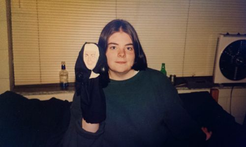 image of me from 1993, sitting on a bed in a cinderblock-walled dorm room, with a punching nun puppet on my hand