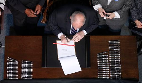 image from above of Democratic Illinois Governor Pat Quinn, a white man, signing marriage equality into law in Illinois on Abraham Lincoln's desk