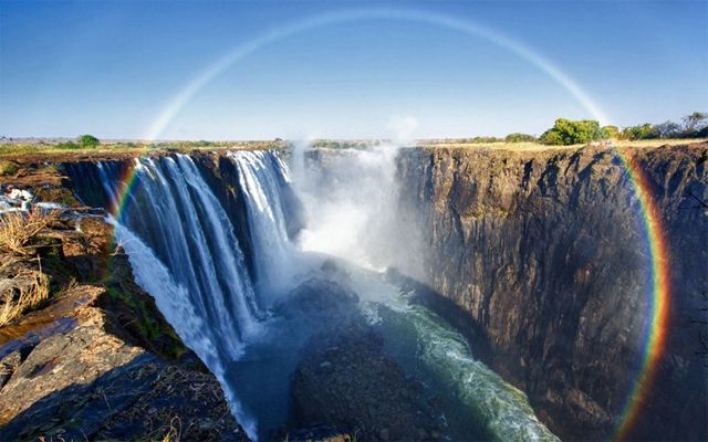 image of a nearly full-circle rainbow above a waterfall