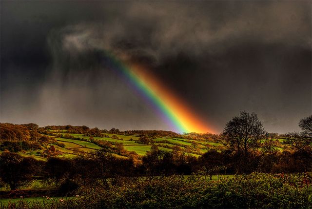 image of a rainbow cutting through dark clouds over an English countryside