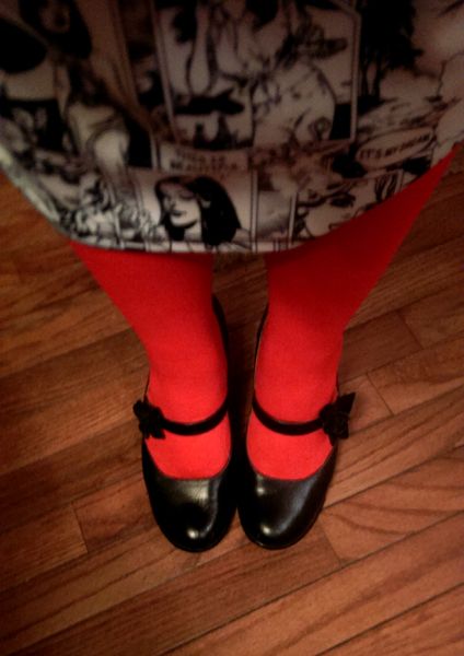 image of my body from the waist down: I'm wearing a black and white comic book skirt, red tights, and black MaryJane shoes with roses where the strap meets the shoe