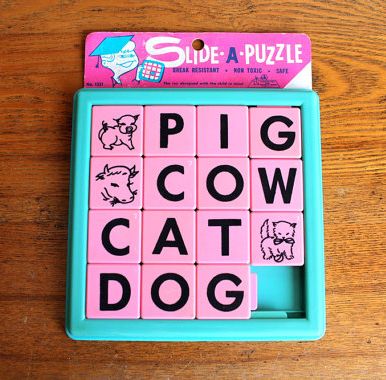 image of a vintage slide tile puzzle with the words PIG, COW, CAT, and DOG on it