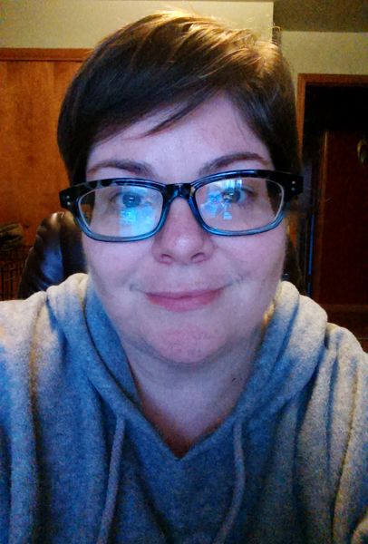 image of me, a fat white middle-aged woman with short hair and glasses, wearing a grey hoodie and sitting in my office