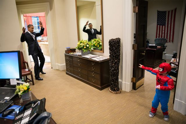 image of President Obama pretending to get hit by a spider web while a tiny child in a Spider-Man costume pretends to shoot a web at him