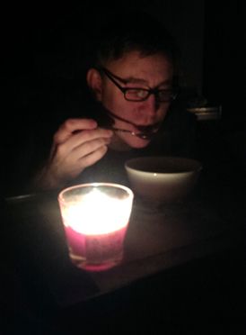 image of Deeky eating soup by candlelight in an otherwise dark room