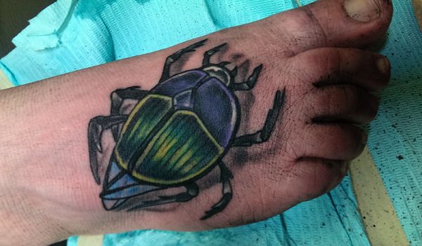 image of my foot sporting a new tattoo of a green and purple beetle