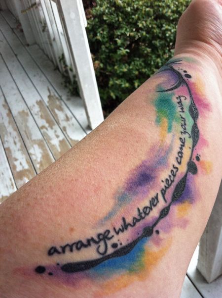 image of my fat white left forearm with the words 'arrange whatever pieces come your way' curving beside a black drippy line from which stretches away blotches of color that look like paint-strokes