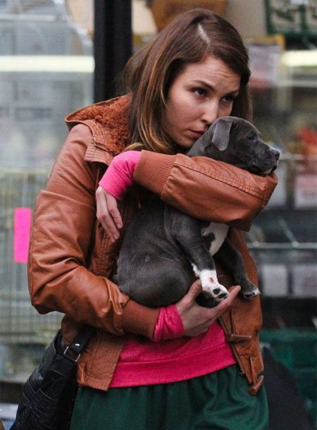 image of actress Noomi Rapace snuggling with an adorable grey pit bull puppy