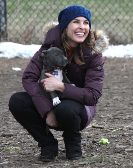 image of Rapace holding the puppy in her arms, grinning broadly