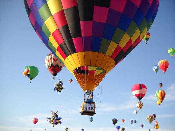 image of a sky full of hot air balloons; Tom Hardy holding a pit bull puppy can just be seen, very tiny, in one of the baskets