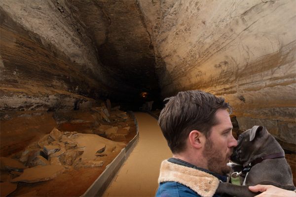 image of Tom Hardy kissing a grey pit bull puppy on the muzzle in front of Mammoth Cave