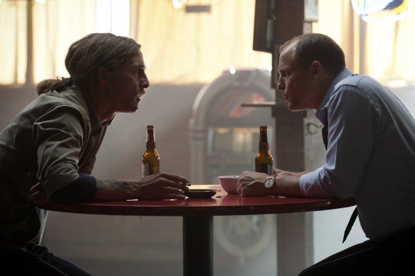 image of Rust (Matthew McConaughey) and Marty (Woody Harrelson) sitting across a table from one another, drinking beer, deep in discussion