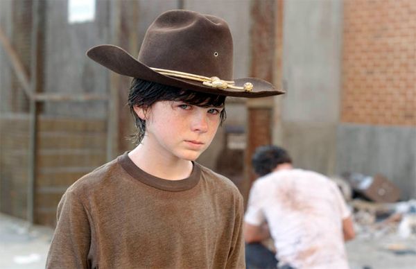 screen cap from the latest episode of The Walking Dead of Carl looking grim while Grimes crouches and flails in the background