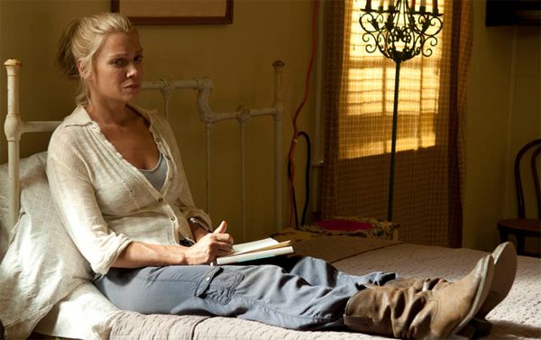 image of Andrea sitting on a bed with a journal in her lap and a pen in her hand