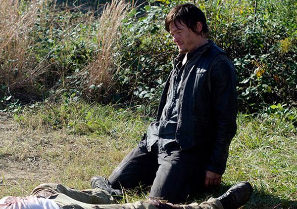 image of Daryl kneeling over a dead body, looking sad