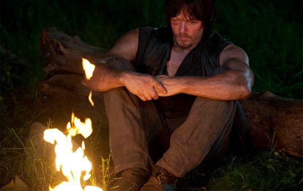 image of Daryl sitting near a campfire, looking despondent