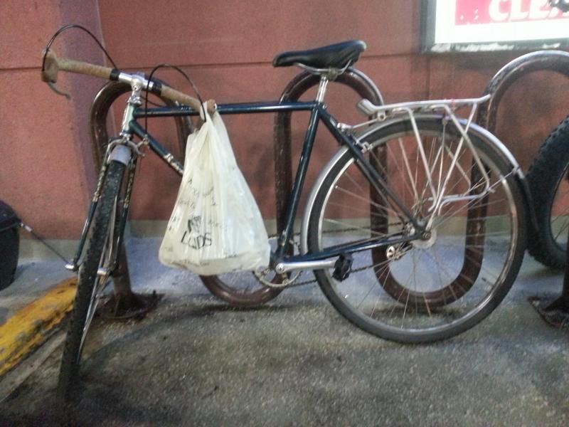 bicycle with a plastic bag hanging from the handle bar