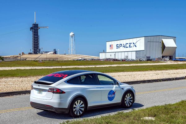 The Tesla Model X that astronauts will ride in on launch day is displayed with SpaceX's Horizontal Integration Facility at Launch Complex 39A in the background.
