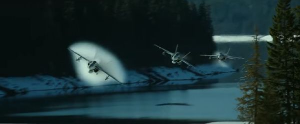 Three F/A-18 Hornets are about to break the sound barrier above a lake in TOP GUN: MAVERICK.