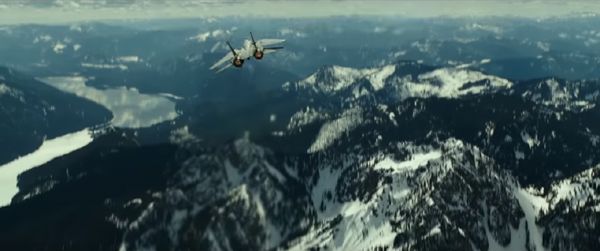An F-14 Tomcat (which, in real life, was retired back in 2006) flies above a snow-covered mountain range in TOP GUN: MAVERICK.