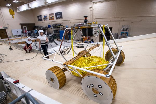Two technicians look on as an engineering model of NASA's VIPER lunar rover is tested at NASA's Glenn Research Center in Cleveland, Ohio.